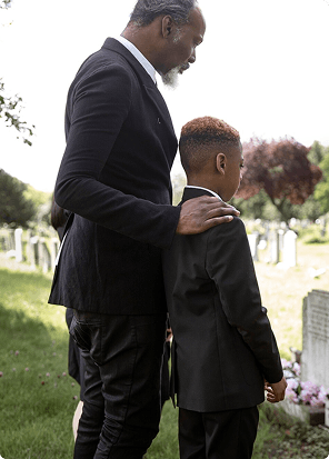 Father comforting his son at a graveside